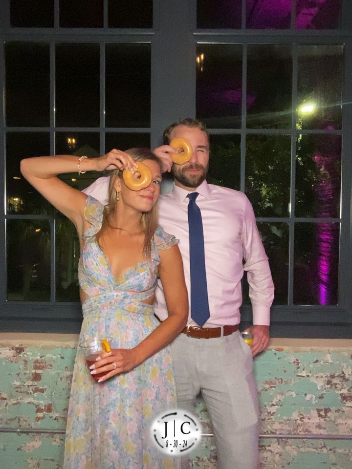 Chris and Lauren at a wedding photo booth, donuts in hand